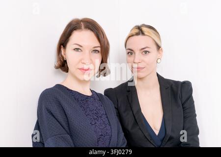 Ritratto ravvicinato di due professioniste, bruna e bionda, in uno studio minimalista Foto Stock