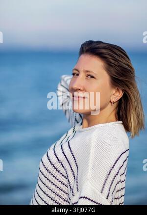 Bella donna in maglione a righe che guarda sopra la spalla Foto Stock