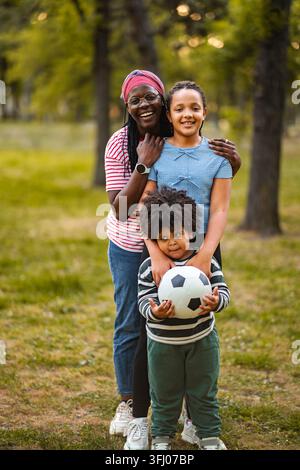 Famiglia felice all'aperto che gioca, mamma con i suoi due figli Foto Stock