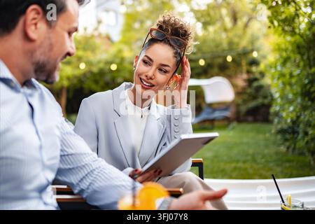 Donna d'affari di successo con un tablet che parla con un collega all'aperto Foto Stock