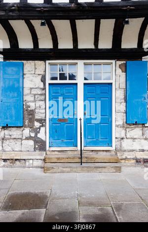 Porte blu e persiane blu su facciata in pietra con travi in legno e gradini York Yorkshire UK Foto Stock