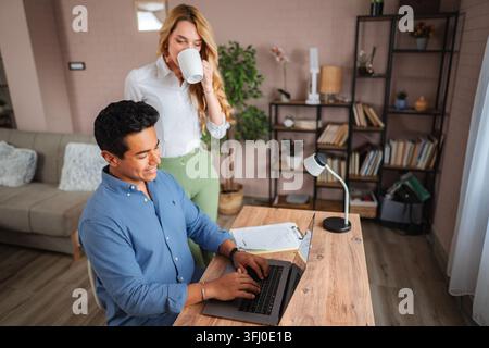 Coppia che sorride, lavora e beve caffè in ufficio a casa Foto Stock