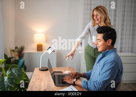 Coppia collaborativa che discute del lavoro al computer fisso in un ufficio domestico Foto Stock