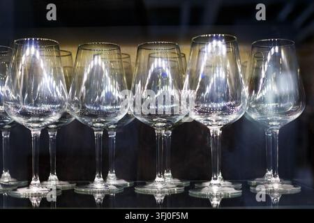 Filiera di bicchieri di vino vuoti in cristallo su un bancone lucido del bar con riflessi di luce Foto Stock