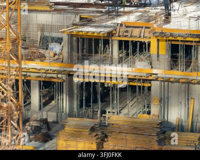 Strutture portanti in cemento con rinforzi in acciaio e pannelli di getto in legno si ergono in un cantiere affollato per illustrare lo sviluppo immobiliare moderno Foto Stock