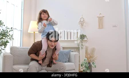 Felice padre seduto sul divano con sua figlia sulle spalle Foto Stock