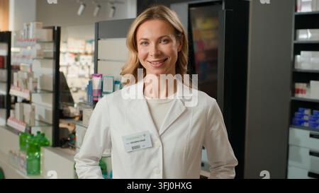 Ritratto di una farmacista caucasica di mezza età ottimista che sorride mentre lavora in farmacia. Farmacista, chimica, apotecaria positiva e allegra che lavora in Foto Stock