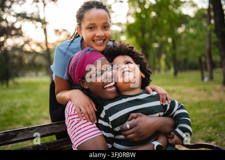 Famosa famiglia afroamericana che ride e si abbraccia nel parco Foto Stock