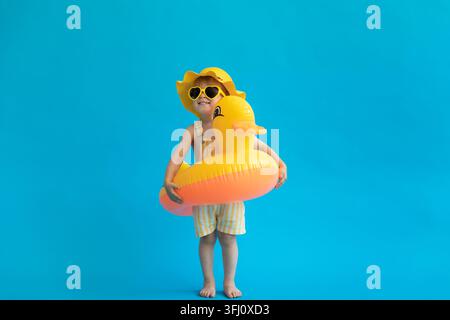 Bambino felice con anatroccolo di gomma giallo su sfondo blu Foto Stock