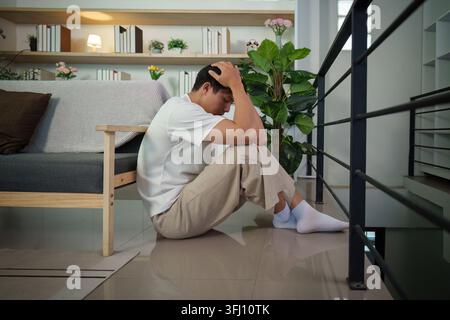 Uomo asiatico sui vent'anni seduto a terra in disperazione e tristezza Foto Stock
