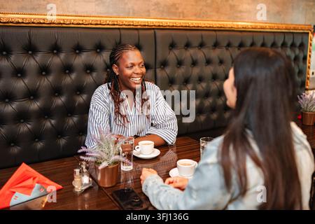 Due amiche felici che conversano in un caffè Foto Stock