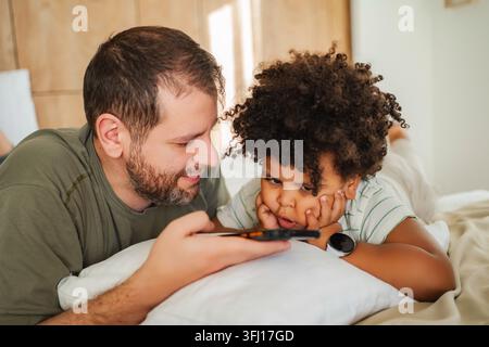 Padre e figlio legano con lo smartphone a casa Foto Stock