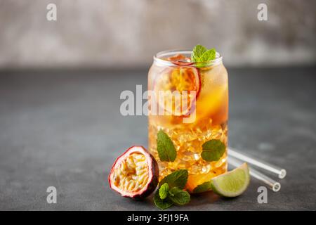 Tè con ghiaccio alla frutta. Rinfrescante bevanda estiva con sciroppo, frutto della passione, lime, menta e ghiaccio. Bicchiere con bevanda fresca e salutare Foto Stock