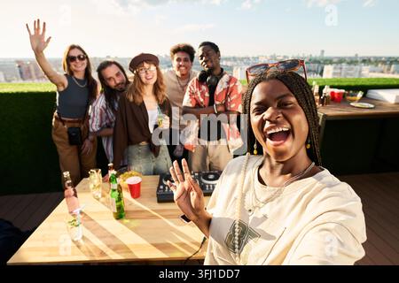 POV di un gruppo diversificato di amici che scattano un selfie a una festa sul tetto Foto Stock
