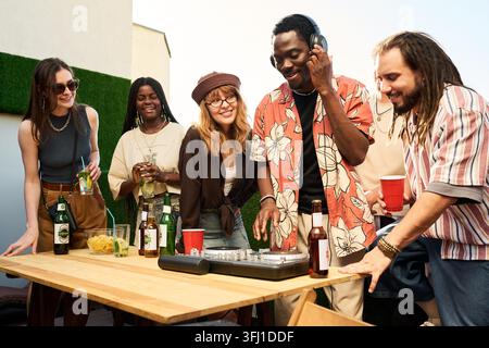 Gruppo diversificato di amici che si diverte a una festa sul tetto con DJ Foto Stock