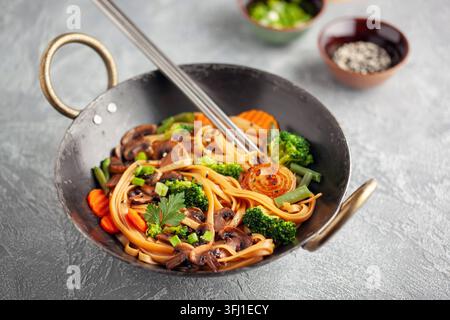 Spaghetti Wok con funghi, broccoli, carote e cipolle verdi. Foto Stock