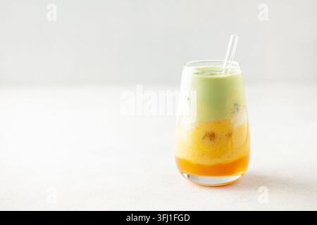 Latte matcha di mango ghiacciato in vetro sul tavolo Foto Stock