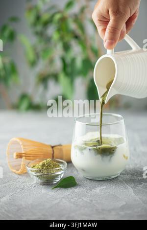 Il tè Matcha viene versato in latte freddo. Sana bevanda vegana Matcha latte Foto Stock