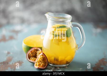 Tè freddo alla frutta con mango, frutto della passione e menta in una tazza di vetro sul tavolo. Foto Stock