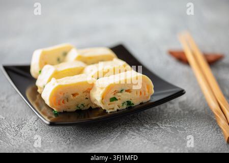 Tamagoyaki, omelette giapponesi arrotolate in piatto sul tavolo Foto Stock