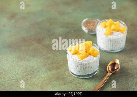 Budino di semi di chia da latte di cocco con cubetti di mango in un recipiente di vetro. Cibo vegano. Concetto di mangiare pulito Foto Stock