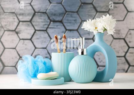 Spazzolini in vetro, sapone liquido in bottiglia, vassoio e fiori in bagno. Accessori per il bagno Foto Stock