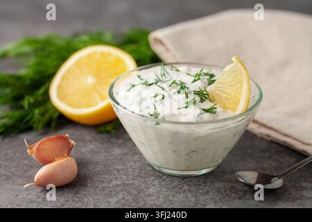 Salsa di panna acida con aneto e aglio in un recipiente sul tavolo. Cibo biologico Foto Stock