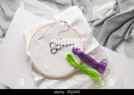 Hobby, artigianato, creatività, concetto di tempo libero a casa. Le mani femminili ricamando il punto trasversale sulla tela. Disposizione piatta, vista dall'alto Foto Stock