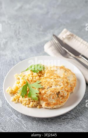Cotolette di pollo o verdure con contorno di bulgur in un piatto sul tavolo. Nutrizione alimentare Foto Stock