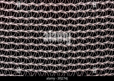 Struttura dettagliata a maglie metalliche isolata su sfondo nero. Anelli ripetuti e forme geometriche creano un motivo astratto moderno. Foto Stock