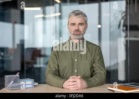 Uomo d'affari seduto alla scrivania in ufficio, manager professionista che lavora su un'analisi finanziaria con documenti e laptop in un moderno ambiente di lavoro aziendale. Leader esperto concentrato sulla strategia aziendale. Foto Stock