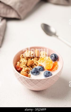 Muesli con farinata d'avena, yogurt, frutti di bosco, frutta e noci in un recipiente sul tavolo. Colazione salutare Foto Stock