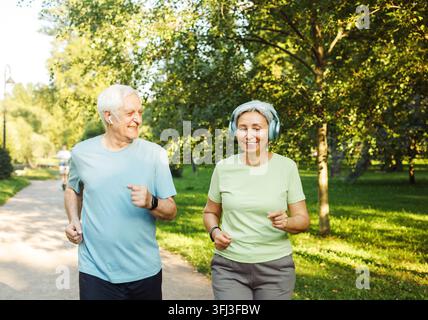 Coppia di anziani che corre insieme nel parco guardandosi a vicenda durante gli esercizi di jogging e dimagrimento. Foto Stock