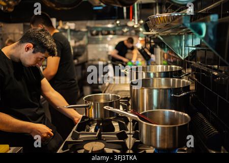 Chef professionisti al lavoro in una cucina di ristorante affollata Foto Stock