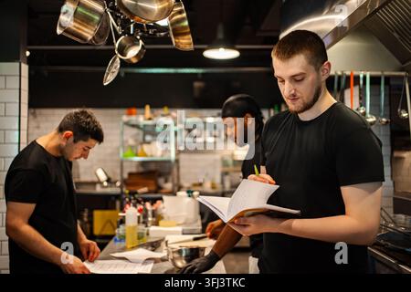 Chef che lavorano in una cucina di ristorante moderna e affollata Foto Stock