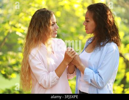 Mamma e sua figlia adulta si tengono per mano in un parco estivo Foto Stock