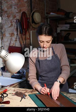 giovane donna bruna lavora in uno studio di produzione di borse, ritaglia dettagli Foto Stock
