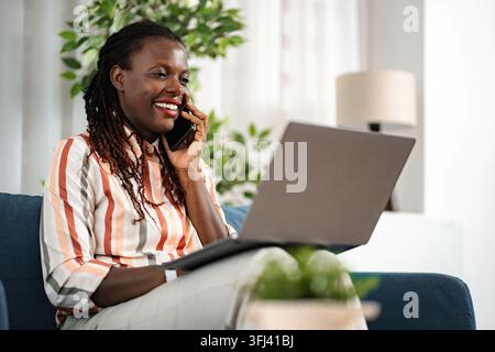 Donna afroamericana che lavora da casa e parla al telefono Foto Stock