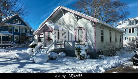 Carina casa in stile bungalow pastello coperta di neve invernale negli USA. Avvicinamento aereo in una giornata di sole, Cape May, New Jersey. Foto Stock