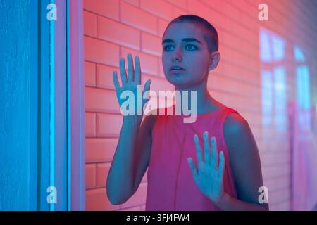 Panico e paura di una donna spaventata nel neon rosa di notte Foto Stock
