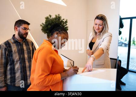 Donna che firma documenti alla reception dell'hotel Foto Stock
