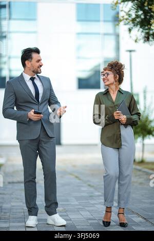 Persone d'affari che conversano camminando all'aperto con un edificio Foto Stock