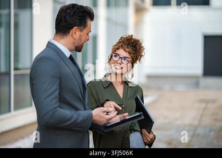 Due professionisti che discutono di lavoro su un tablet all'aperto Foto Stock