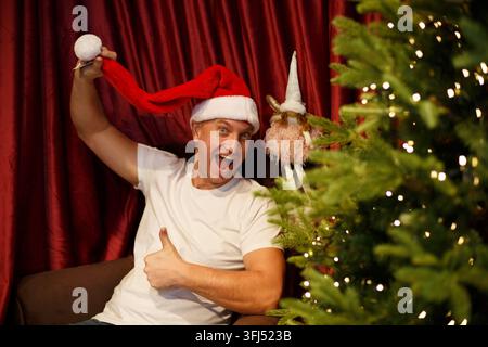 Uomo caucasico entusiasta con un cappello da Babbo Natale e un gesto del pollice Foto Stock
