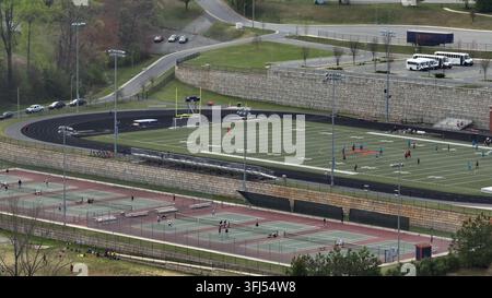 Bambini e studenti che giocano a calcio e tennis su un campo all'aperto in una scuola superiore americana. Giorno di primavera in una giornata soleggiata a Lynchburg, Virginia. Vista aerea ampia Foto Stock
