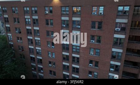 Primo piano aereo di un edificio residenziale in mattoni con appartamenti multipli, con numerose finestre e unità di climatizzazione. Ambiente di vita urbana tipico ad Ameri Foto Stock
