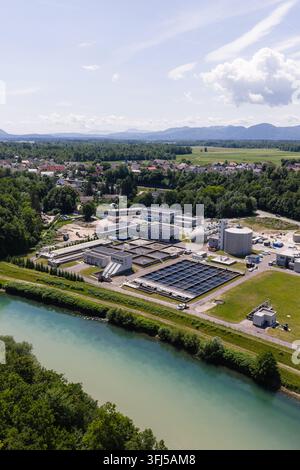 L'impianto trattiene le acque reflue e purifica l'acqua, situato vicino a un fiume e circondato da campi verdi alla luce del giorno. Foto Stock