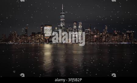 Vista notturna dello skyline di Manhattan durante la nevicata, vista dalla riva del New Jersey con riflessi sul fiume Hudson e l'One World Trade Center illuminato Foto Stock