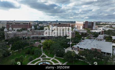 Vista aerea dell'Università di Tampa con una grande bandiera americana che sventola sopra gli edifici storici in mattoni rossi, palme e il paesaggio urbano circostante sotto le nuvole Foto Stock