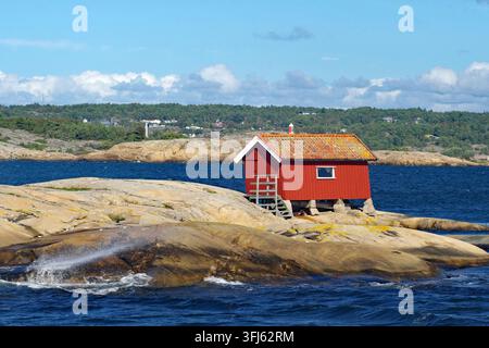 Capanna rossa su rocce sulla costa sotto un cielo sereno, Strömstad, Parco nazionale di Kosterhavet, Svezia Foto Stock